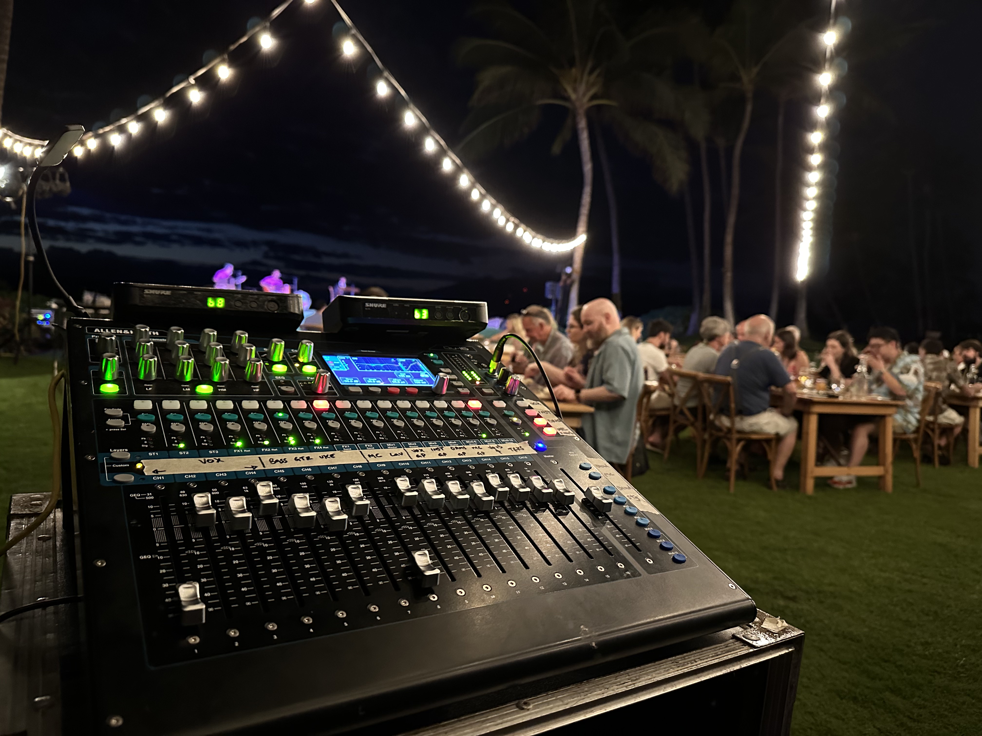 Audio technician adjusting a mixing console during event setup in a busy backstage area