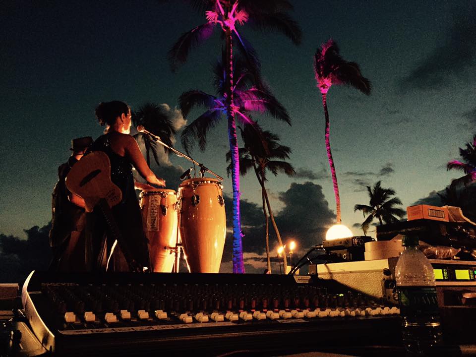 Outdoor stage setup with speaker stacks and evening sky visible behind the equipment